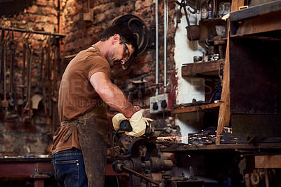Buy stock photo Cropped shot of a handsome young metal worker using a blowtorch while working inside a welding workshop