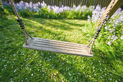 Buy stock photo Old wooden swing in a garden with blue flowers and moss in a lush backyard. Peaceful scene of an outside playground with vibrant wild bluebells and overgrown lawn in spring with copy space