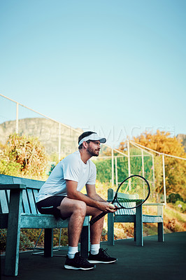 Buy stock photo Shot of a sporty young man sitting on a bench on a tennis court