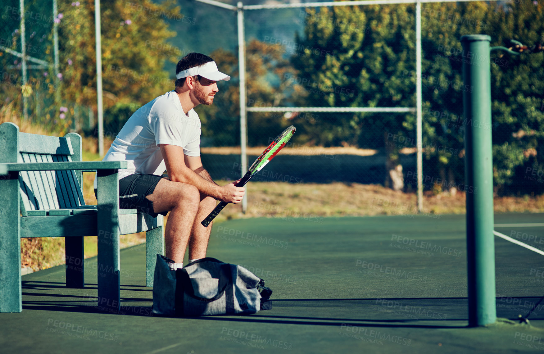 Buy stock photo Man, tennis and waiting with racket for sport, game or match on bench at outdoor court. Young, male person or athlete with bat for break, rest or half time in competition, tournament or practice