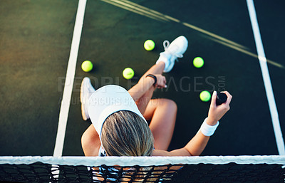 Buy stock photo High angle shot of a sporty young woman sitting on a tennis court with tennis balls around her