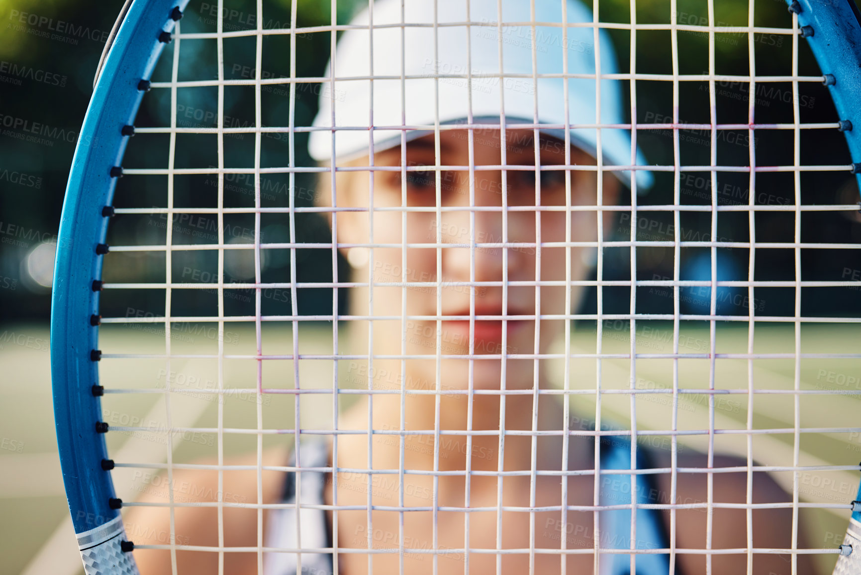 Buy stock photo Closeup shot of a tennis racket with a sporty young woman standing in the background
