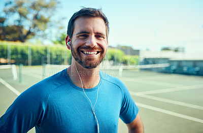 Buy stock photo Portrait of a sporty young man listening to music while exercising on a tennis court
