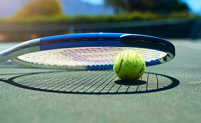 Buy stock photo Cropped shot of a tennis racket and ball on an empty court during the day