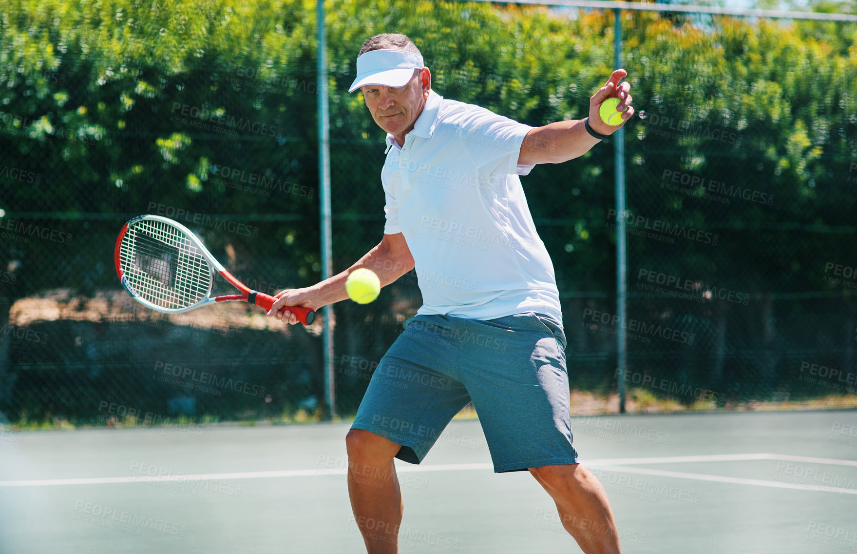 Buy stock photo Cropped shot of a handsome mature man playing tennis alone on a court during the day