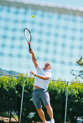 Buy stock photo Cropped shot of a handsome mature man playing tennis alone on a court during the day