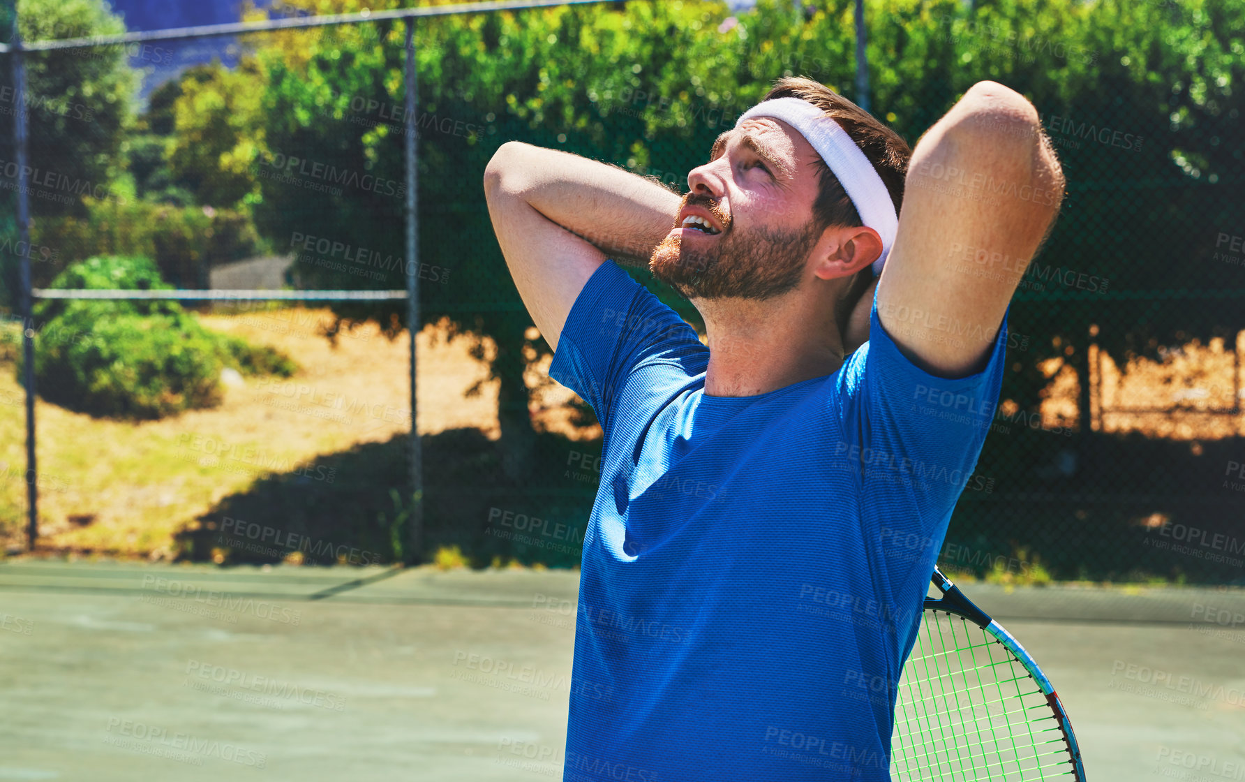 Buy stock photo Cropped shot of a handsome young man standing alone on a tennis court during the day