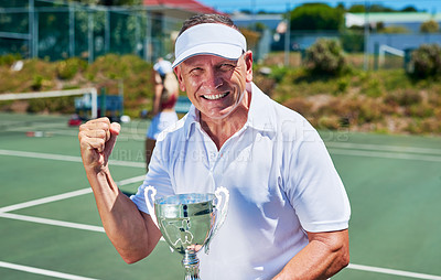 Buy stock photo Cropped portrait of a handsome mature man holding up a trophy after winning a tennis match during the day