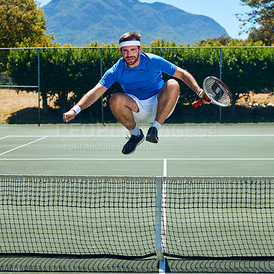 Buy stock photo Full length shot of a handsome young man jumping over a tennis net while on the court during the day