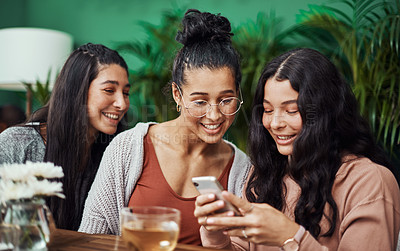 Buy stock photo Shot of young sisters using a smartphone together at a cafe