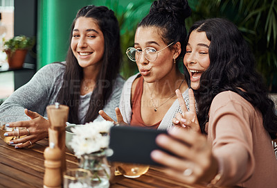 Buy stock photo Shot of young sisters taking selfies together at a cafe