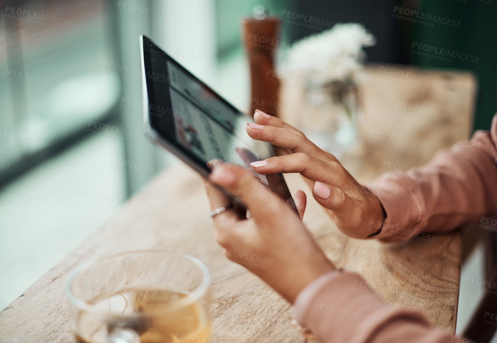 Buy stock photo Cropped shot of a woman using a digital tablet at a cafe