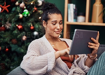 Buy stock photo Shot of a beautiful young woman using a digital tablet on the sofa during Christmas at home