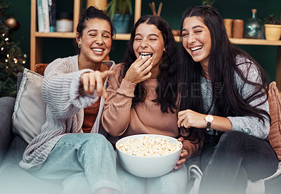 Buy stock photo Shot of young sisters having popcorn and watching tv together during Christmas at home