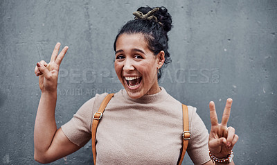 Buy stock photo Cropped portrait of an attractive teenage girl feeling playful and making a peace sign gesture against a gray city wall