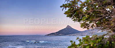 Buy stock photo Wide angle of a mountain on a coastline at sunset in South Africa. Scenic nature landscape of Lions Head at dawn near a calm peaceful sea against a blue horizon with copy space in Cape Town