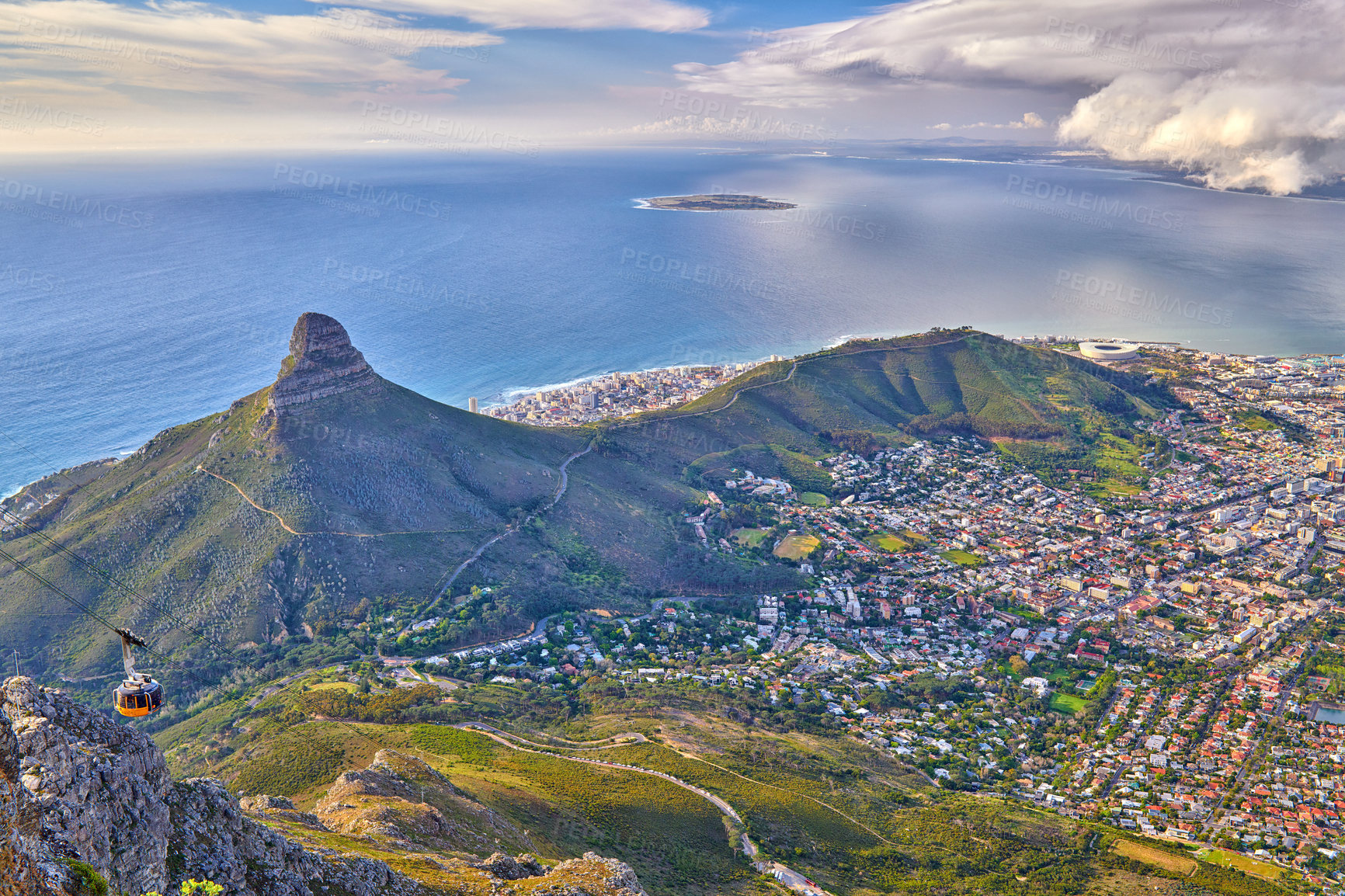 Buy stock photo Aerial view of Lions Head mountain with the ocean and a cloudy sky copy space. Beautiful landscape of green mountains with vegetation surrounding an urban city in Cape Town, South Africa