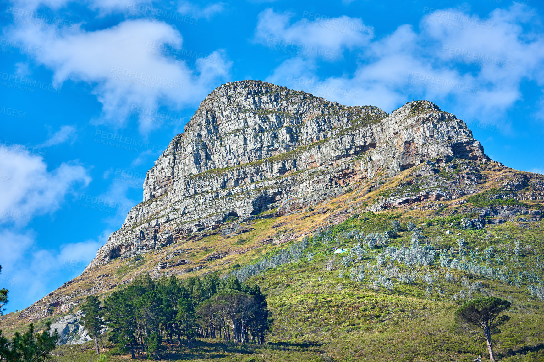 Buy stock photo Landscape of a mountain on cloudy blue sky with copy space. Beautiful nature view of Lions Head mountains peak with lush green trees and bushes in a popular hiking location in Cape Town, South Africa