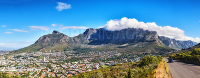 Buy stock photo A mountain road overlooking the city with a cloudy blue sky. Panoramic landscape of green mountains surrounding an urban town and a scenic road for traveling along Cape Town, South Africa
