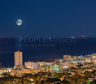 Buy stock photo Urban city lights with a full moon in the midnight sky copy space. Skyline with colorful lighting with the wide open ocean on the horizon. Modern metroplitan architectural buildings at night