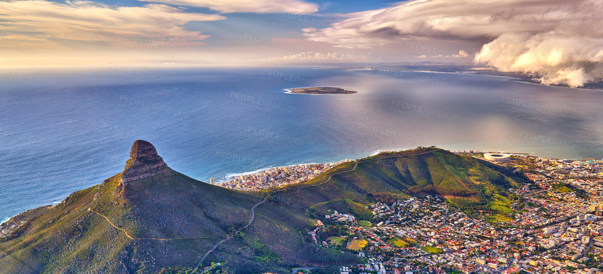 Buy stock photo Aerial view of Lions Head mountain with the ocean and cloudy sky copy space. Beautiful landscape of green mountains with lots of vegetation surrounding an urban city in Cape Town, South Africa
