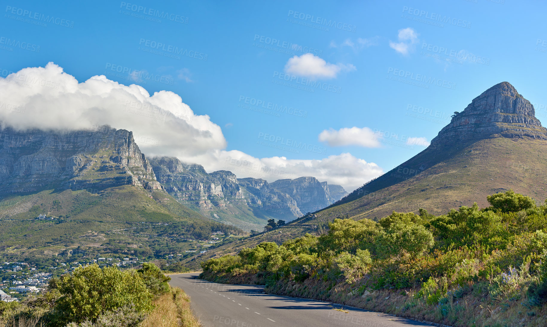 Buy stock photo A road along a mountain and green nature with a cloudy blue sky and copy space. Beautiful landscape of a peaceful tarred roadway near plants and the wilderness on a summer day