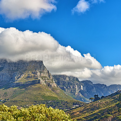 Buy stock photo Thick clouds rolling over Table Mountain, Cape Town with copyspace. Cloud shadows passing rocky terrain on sunny day, beautiful, peaceful nature in harmony with soothing view of plants and landscape