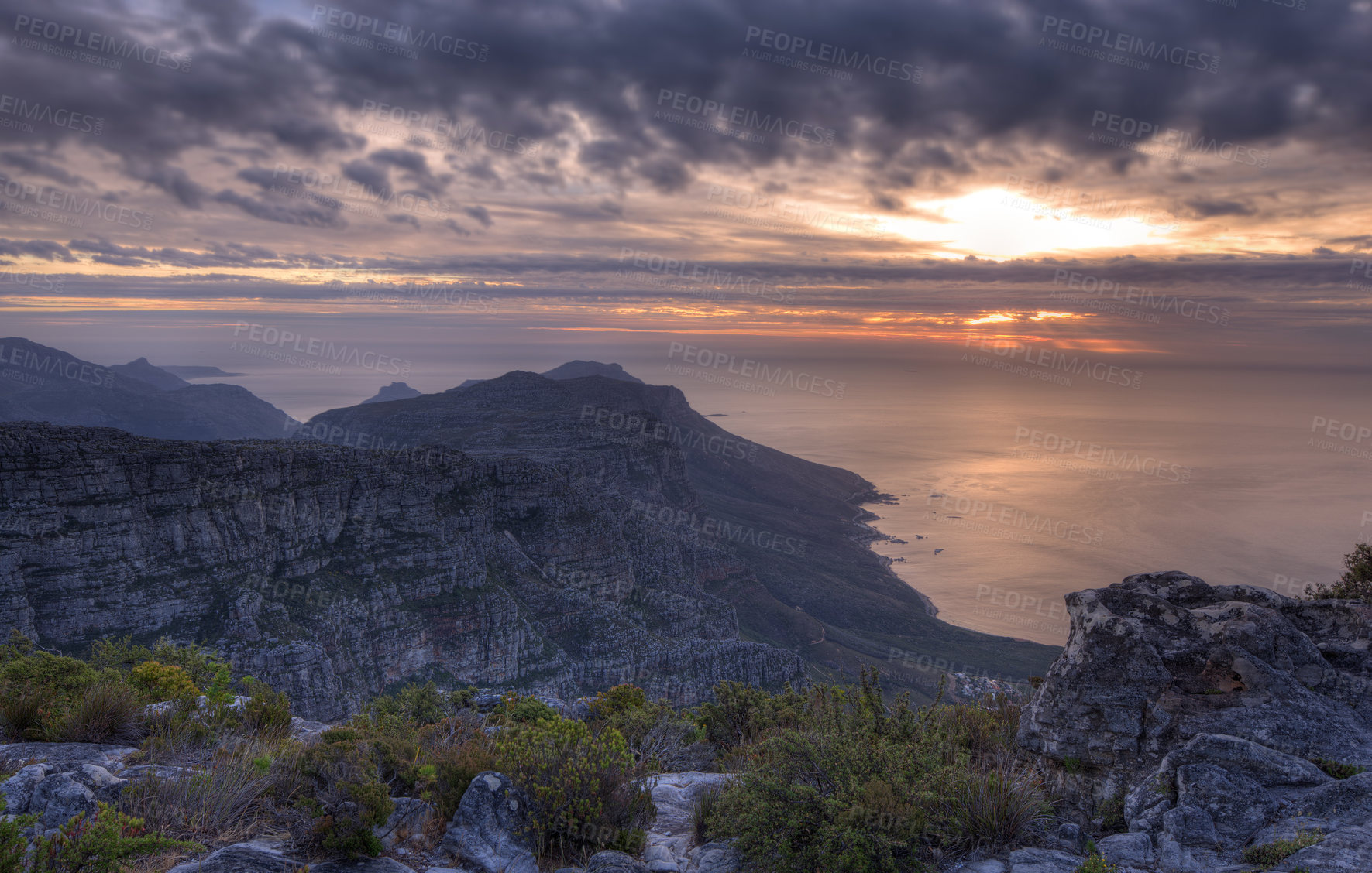 Buy stock photo Above view of a mountain coastline at sunset in South Africa. Scenic landscape of dark clouds over a calm and peaceful ocean near Cape Town with the sun behind grey clouds in the sky and copy space