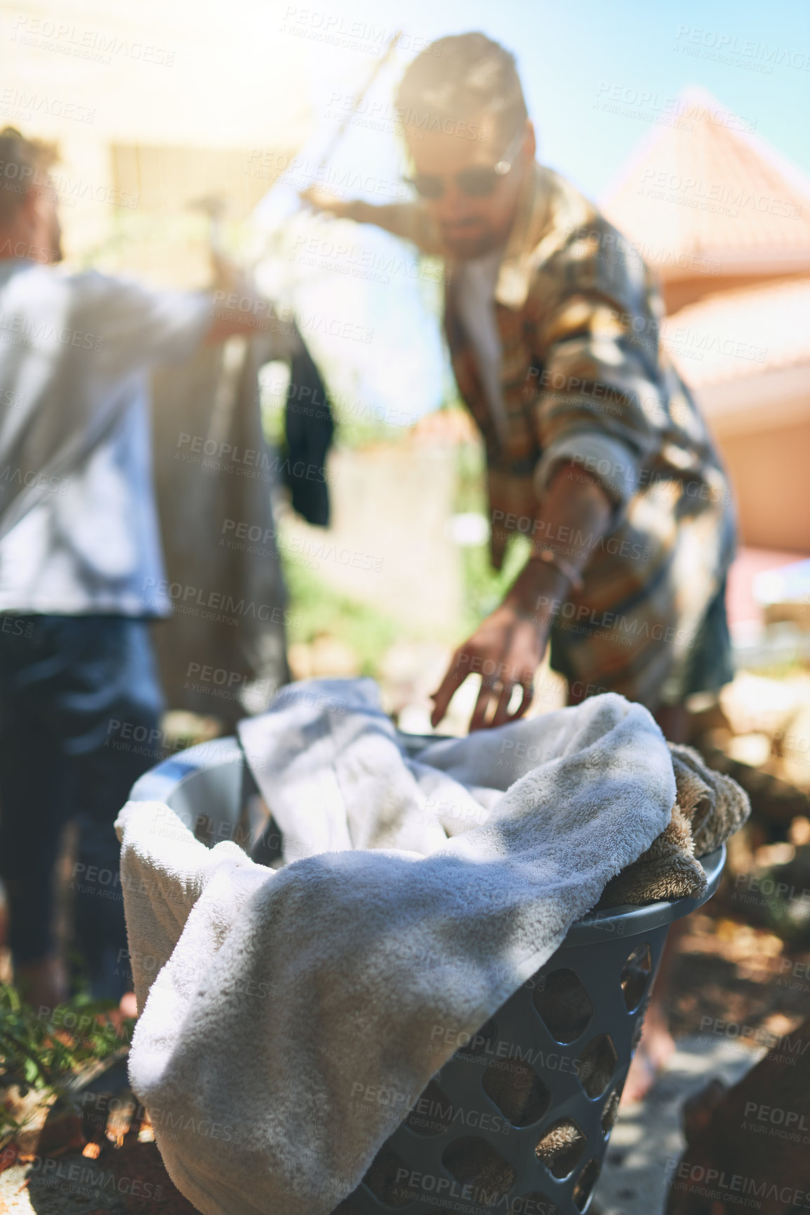 Buy stock photo Outdoor, men and laundry for hanging to dry, sunlight benefits and fresh air for cotton fabric. Flare, friends and basket with wet towels after cleaning, washing line and responsibility with support