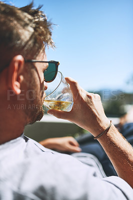 Buy stock photo Cropped shot of a relaxed young man having a drink while looking at the view from his balcony outside at home during the day