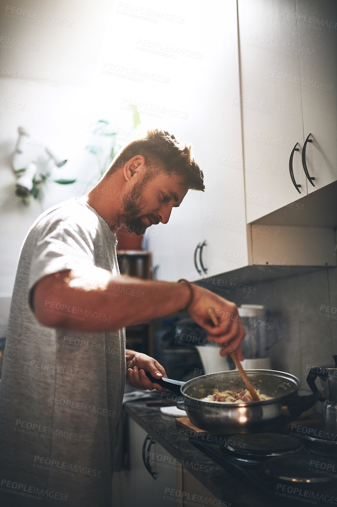 Buy stock photo Cropped shot of a cheerful young man cooking food inside of the kitchen at home
