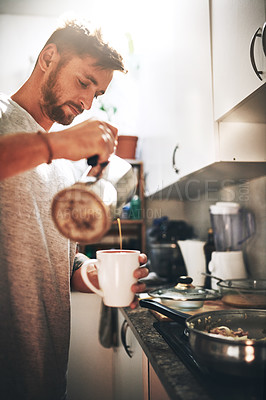 Buy stock photo Cropped shot of a cheerful young man pouring coffee into a cup inside of the kitchen at home