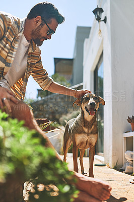 Buy stock photo Cropped shot of a cheerful young man petting his dog outside of his home during the day