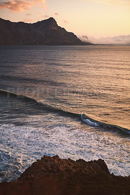 Buy stock photo Cropped shot of a mountain range near the sea during the early hours of the evening