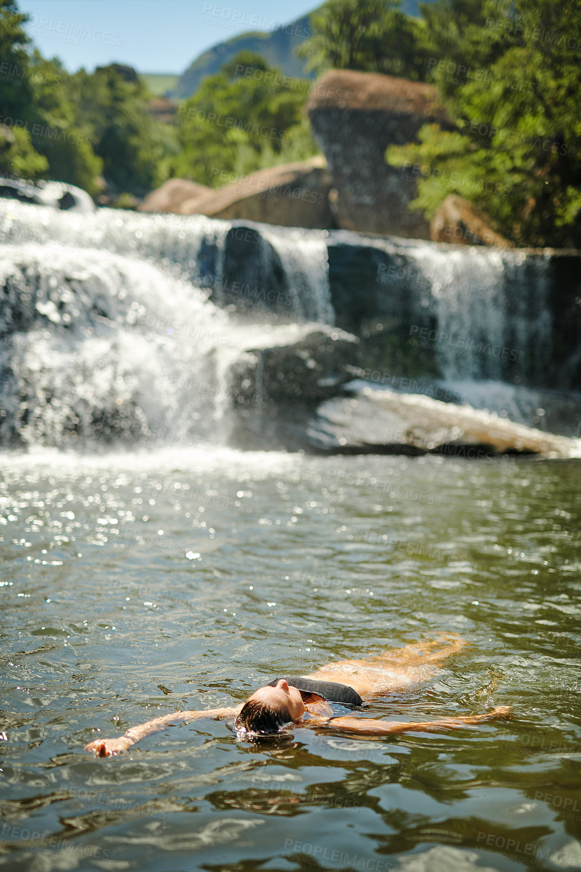 Buy stock photo Full length shot of an unrecognizable woman swimming in a stream alone during a day outdoors