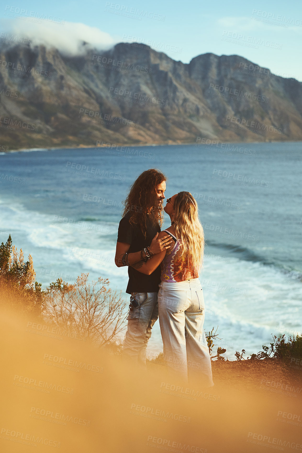 Buy stock photo Cropped shot of an affectionate young couple standing on the mountainside near a sea together during a day outdoors