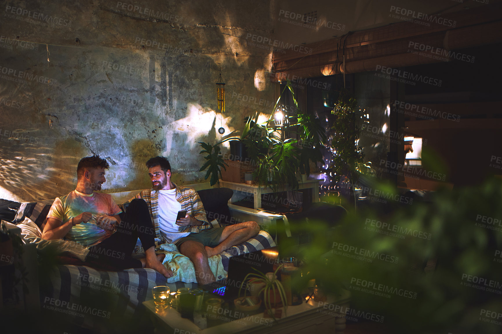 Buy stock photo Night, phone and men on couch together for conversation, weekend hangout and bonding in home. Relax, chat and male friends with smartphone, sharing social media or talking on sofa in dark living room