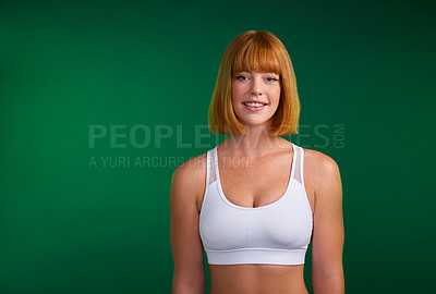 Buy stock photo Cropped portrait of an attractive young sportswoman standing alone against a green background in the studio