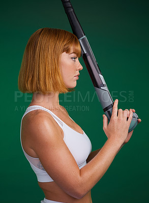 Buy stock photo Cropped shot of an attractive young sportswoman standing alone and posing with hockey stick against a green studio background