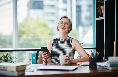 Buy stock photo Shot of a businesswoman having coffee while using her cellphone in her office