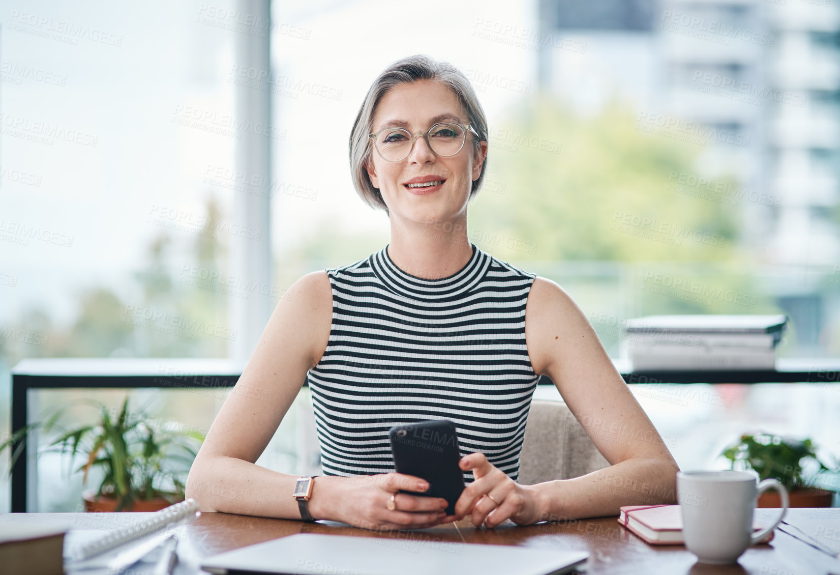 Buy stock photo Shot of a mature businesswoman using her cellphone while sitting at her desk