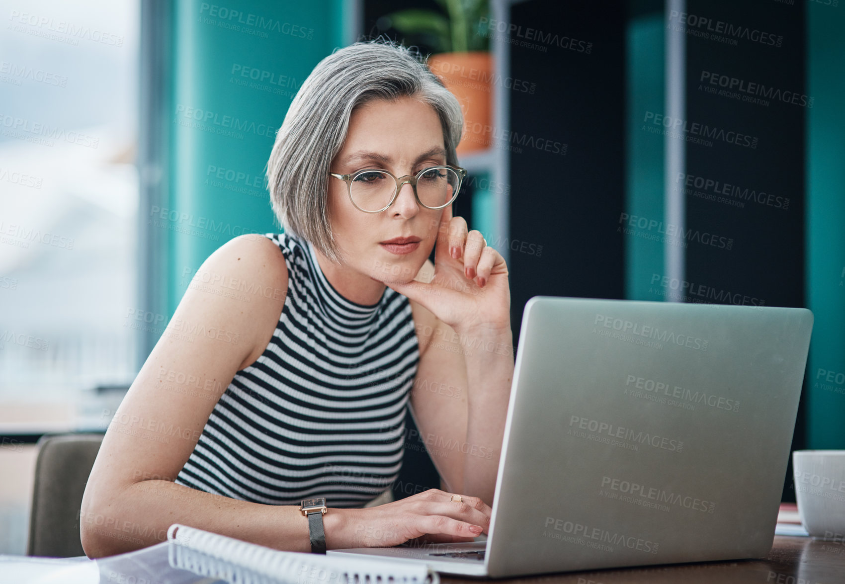 Buy stock photo Shot of a mature businesswoman using her laptop while sitting at her desk