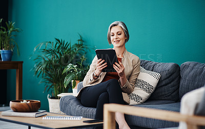Buy stock photo Cropped shot of an attractive mature businesswoman sitting alone and using a tablet in her home office