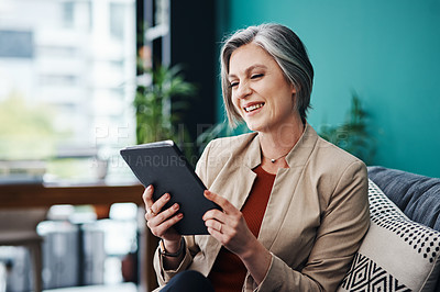 Buy stock photo Cropped shot of an attractive mature businesswoman sitting alone and using a tablet in her home office