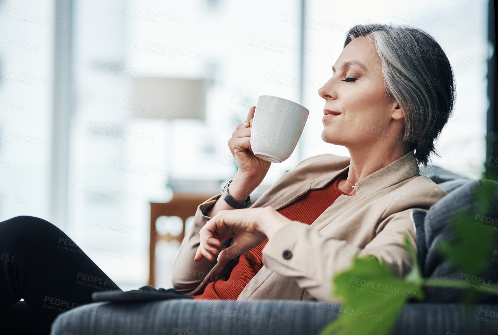 Buy stock photo Cropped shot of an attractive mature businesswoman sitting alone and enjoying a cup of coffee in her home office