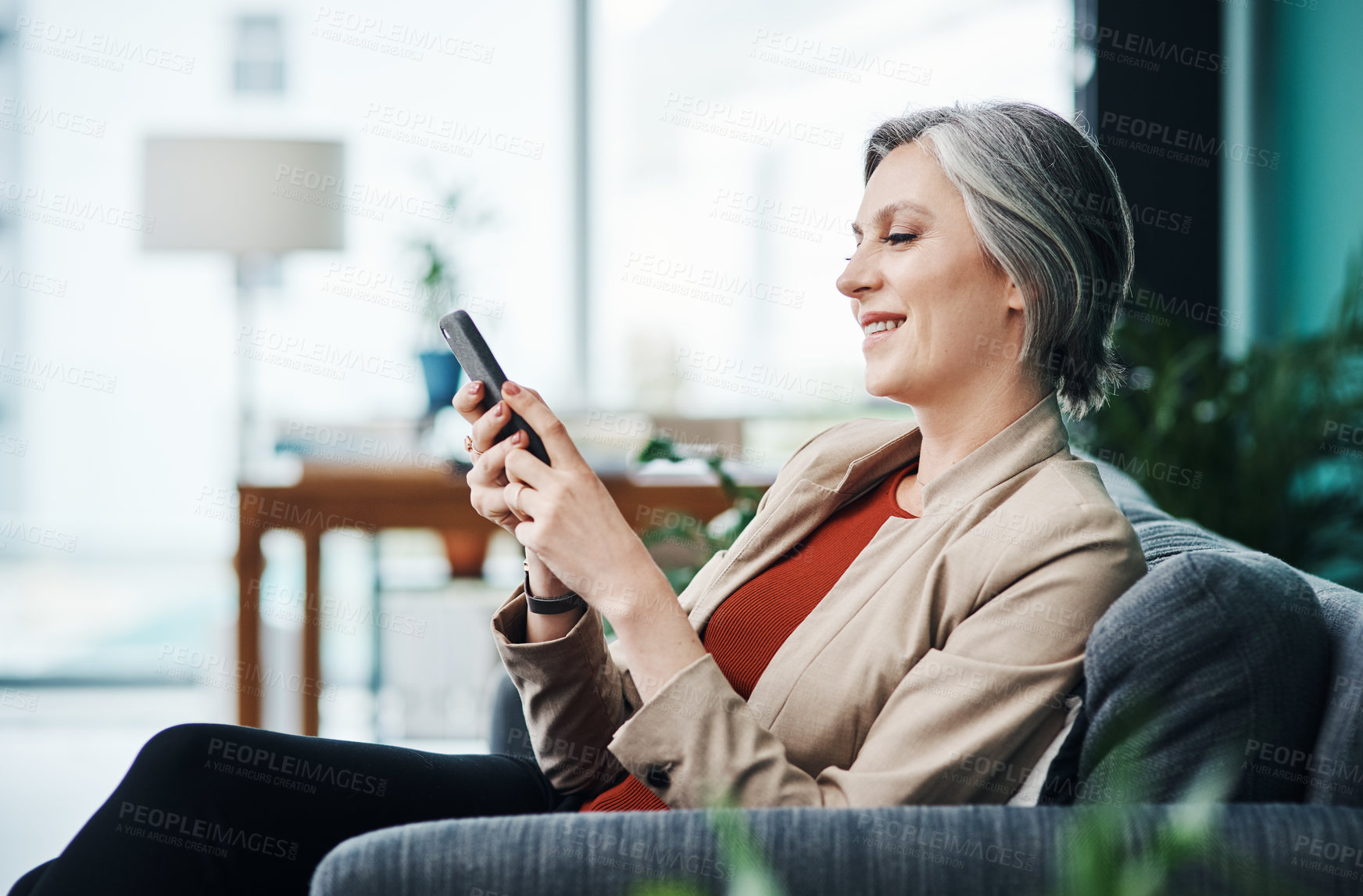 Buy stock photo Cropped shot of an attractive mature businesswoman sitting alone and using a cellphone in her home office