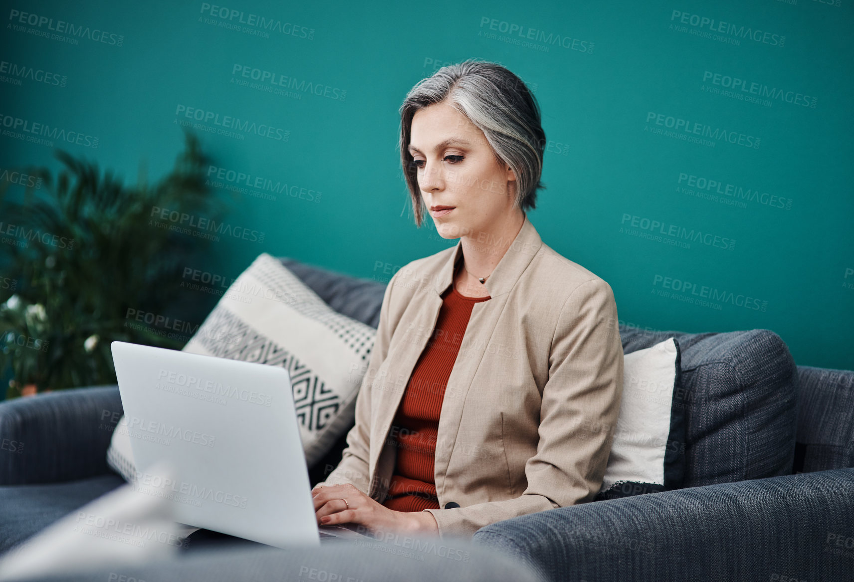 Buy stock photo Cropped shot of an attractive mature businesswoman sitting alone and using a laptop in her home office