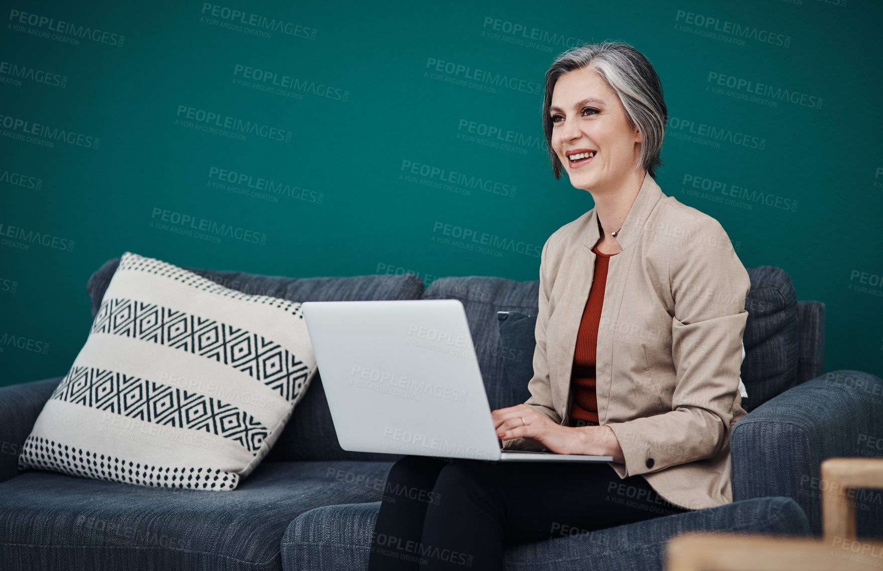 Buy stock photo Cropped shot of an attractive mature businesswoman sitting alone and using a laptop in her home office