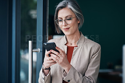 Buy stock photo Cropped shot of an attractive mature businesswoman standing alone and using her cellphone in her home office