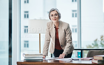 Buy stock photo Cropped portrait of an attractive mature businesswoman standing and reading paperwork by her desk in her home office